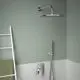 Duschbereich mit einer runden Regendusche in Chromfarbe, montiert an der Wand. Darunter eine Handbrause und ein Wasserhahn von Ideal Standard. Heller Fliesenboden.